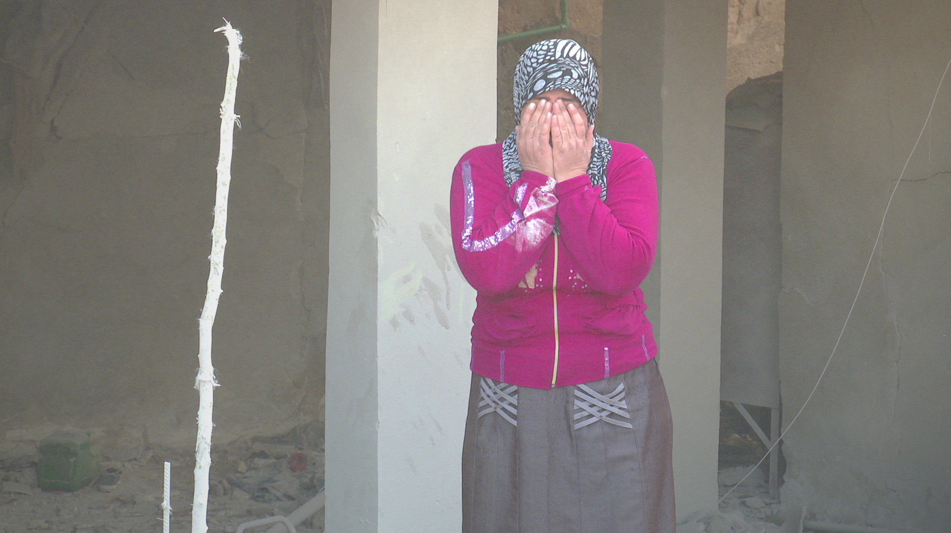 Woman in hijab holding face in grief