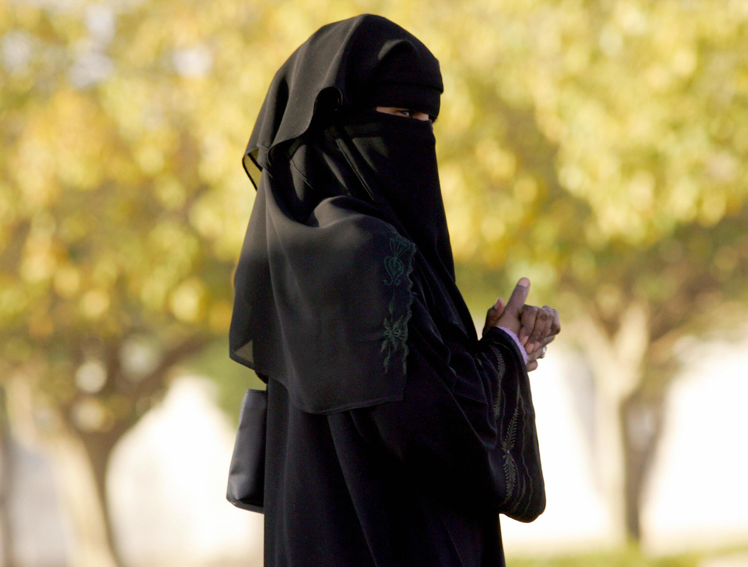 A Saudi woman walks outside a polling st
